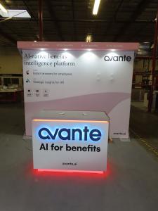 Custom Inline Exhibit with SEG Fabric Backwall, Laminated Header, Puck Lights, Monitor Mount, and Modifited MOD-1596 Counter with RGB Halo Light Logo and Locking Storage -- View 2